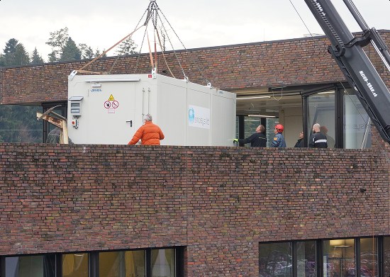 A smolsys laboratory container being lifted onto a building by a mobile crane