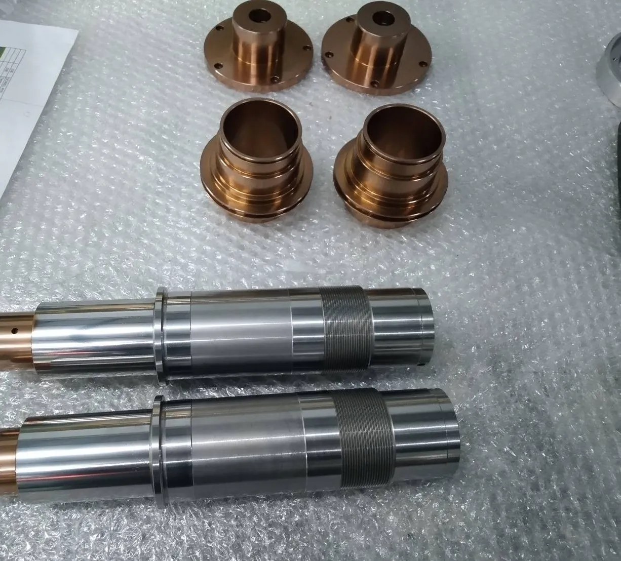 Machined parts: bronze flange bushings and polished stainless steel shafts, ready for assembly
